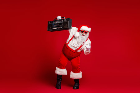 Santa with a retro boombox dances in a red studio creating festive energy for Christmas season and holiday celebrationの写真素材