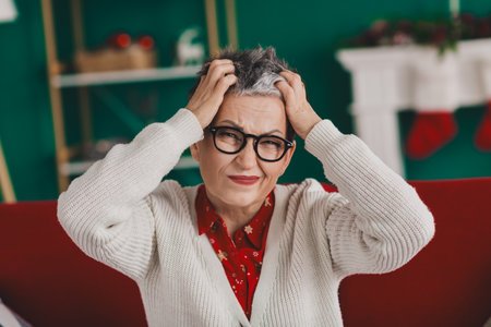 Elderly Woman at a Festive Holiday Setting Feeling Playful and Cheerful in a Cozy Home Atmosphereの写真素材