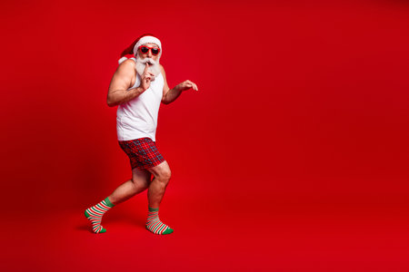Playful Santa look with red background wearing plaid shorts and striped socks in festive moodの写真素材