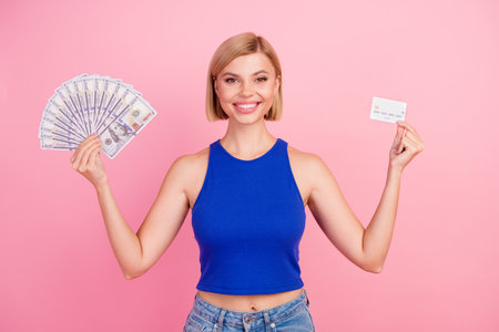 Portrait of nice young girl hold money bills debit card wear blue top isolated on pink color backgroundの写真素材
