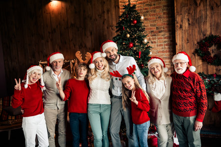 Family Christmas celebration with tree decor and festive group wearing Santa hats and reindeer...