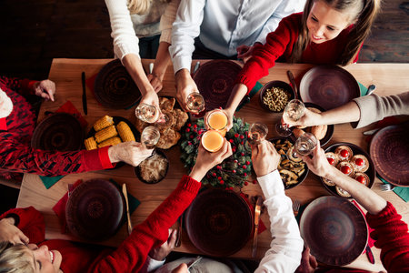 Family gathering around a festive Christmas dinner with friends and loved ones to celebrate together at a cozy tableの写真素材