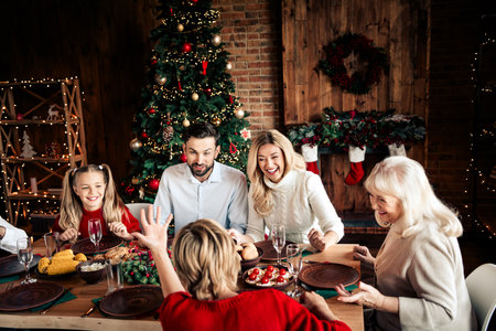 Family Christmas dining scene around a festive table with a decorated tree and warm home ambianceの写真素材