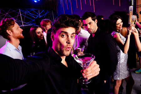 Group of stylish friends celebrate in a neon nightclub to dance drink and share a lively party moment under colorful lights and upbeat musicの写真素材