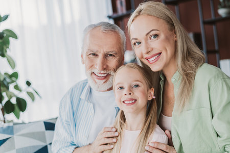 Warm family moment with grandma mom and daughter smiling together at home in a cozy living room with...
