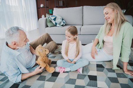 Fun loving family moment with grandma mom and daughter playing with a teddy bear in a cozy home...