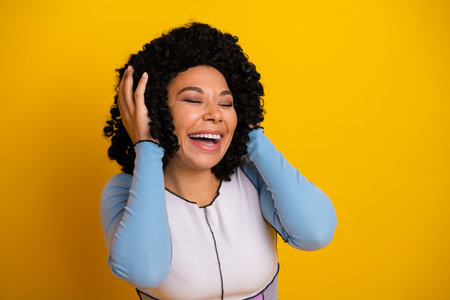 Charming girl smiling joyfully against a yellow background wearing stylish casual outfit and exuding happinessの写真素材