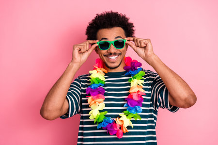 Cheerful young man in striped shirt with colorful lei sunglass against pink backgroundの写真素材