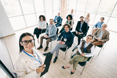 Confident female trainer leads a workshop for business professionals in a modern office setting, focusing on collaboration and teamworkの写真素材