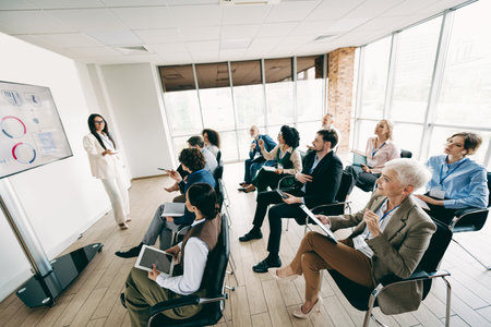 Diverse Professionals Attending a Business Training Seminar Presented by a Female Coach in a Modern Office Settingの写真素材