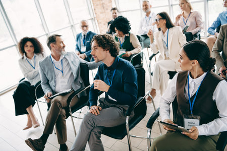 Diverse business team attentively listening to a conference speaker in a modern professional workspaceの写真素材
