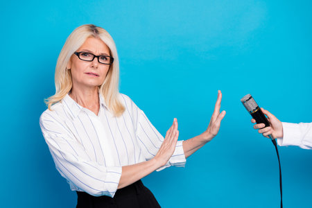 Confident mature businesswoman pauses during a microphone reveal in a professional setting for a dynamic contemporary stock photoの写真素材