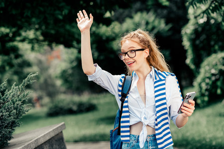 Modern student enjoying a sunny day outdoors connecting with friends in casual attireの写真素材