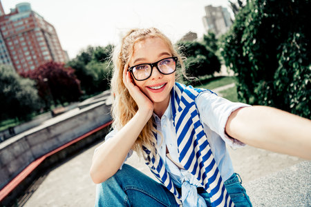 Beautiful girl enjoying a sunny day outdoors with cheerful energy and fashionable styleの写真素材