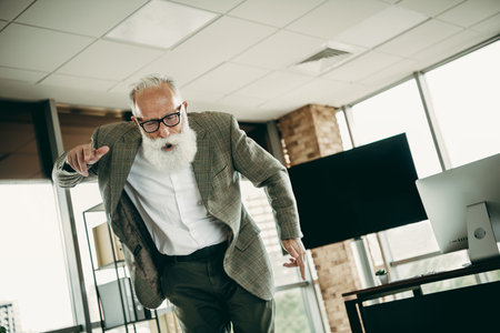 Elegant senior businessman making a statement in a modern office environment, showcasing professionalism and dynamic leadershipの写真素材