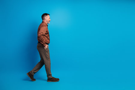 Businessman walking in brown shirt against blue background for corporate branding and executive lifestyle imagery highlightingの写真素材