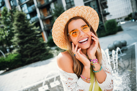 Joyful street style model wearing sunhat and sunglass in sunny city plaza enjoying vacation fashion momentsの写真素材