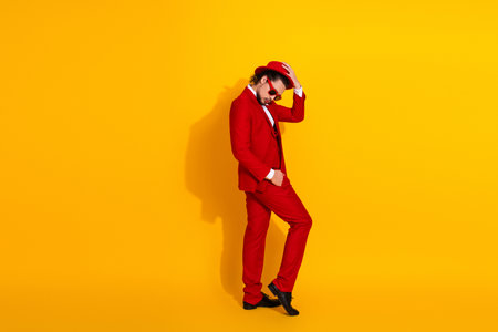Funny stylish man in red suit wears sunglasses and a hat against bright yellow background creating a bold fashion statement for advertising and street style photoshootの写真素材