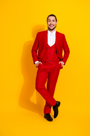 Bold red suit showman breaks the mold with bright playful style against a vibrant yellow backdropの写真素材