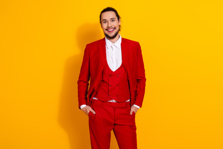 Funny bold stylish red suit man stands against bright yellow background in a confident pose for a vibrant promotional imageの写真素材