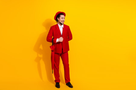 Funny bold fashion moment with a stylish man in a red suit posing against a bright yellow background for a playful holiday themed business styleの写真素材