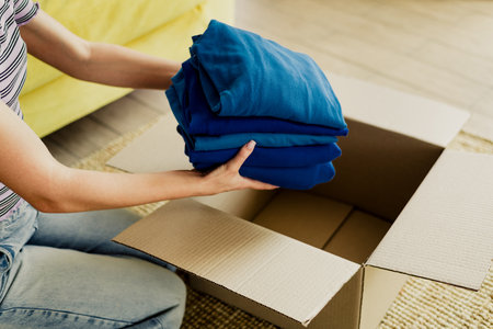 Packing blue clothes into a box at home a cozy moving day scene with interior calm and organized spaceの写真素材