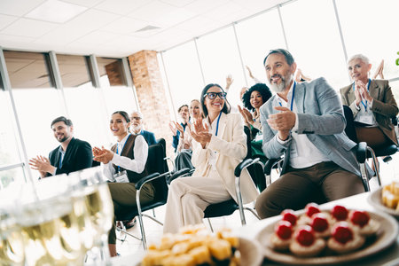 Group of business professionals celebrating success in an office with food and refreshments, showcasing teamwork and collaborationの写真素材