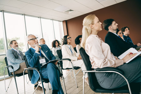 Diverse group of professionals attending a focused business training session in a modern corporate office environmentの写真素材