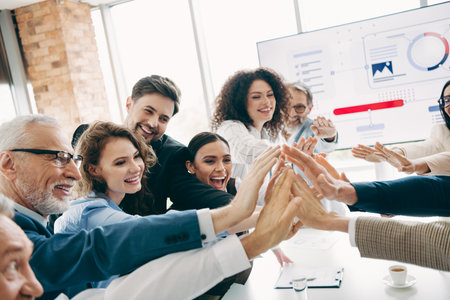 Group of business professionals celebrating teamwork success during a corporate meeting in a bright...