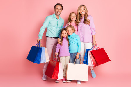 Family shopping celebration smiles together mother father children in colorful outfits against pink backgroundの写真素材