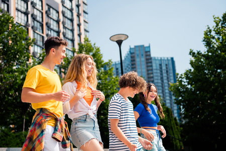 Happy people enjoying a sunny day in the city, walking together with joy and laughter outdoors amidst urban landscapesの写真素材