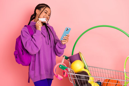 Young woman with braids smiling while shopping in stylish casual hoodie with vibrant props