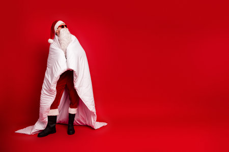 Santa in red suit with white cloak and hat on a bold red background creates a festive christmas mood for holiday partiesの写真素材