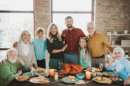 joyful family thanksgiving dinner gathering around a festive table with turkey and smilesの写真素材