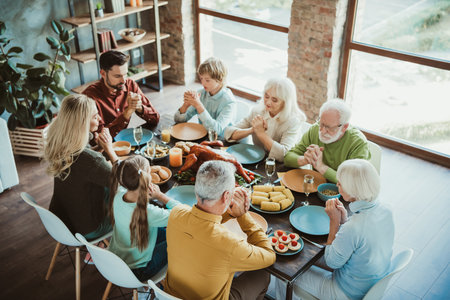 A big joyful family gathers around a long table for thanksgiving dinner celebrating gratitude love...