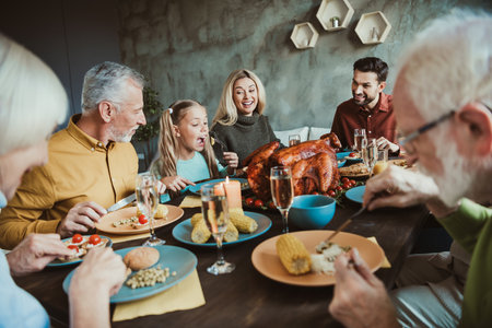Family Thanksgiving feast around a big table with grandparents grandchildren friends celebrating together at homeの写真素材