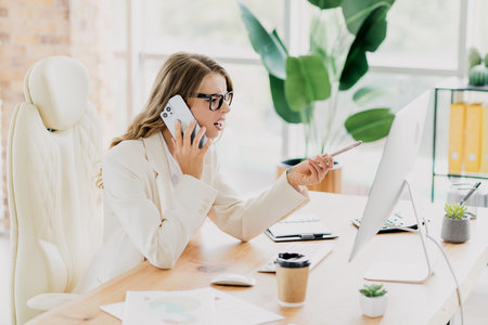 Professional businesswoman multitasking at her stylish workspace with modern devices and toolsの写真素材