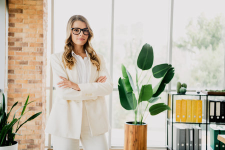 Confident young businesswoman standing in an elegant modern office interior with a professional and authoritative demeanorの写真素材