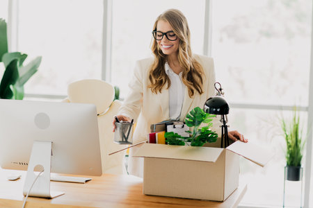Businesswoman packing desk items while transitioning to a new role in a modern and stylish workspaceの写真素材
