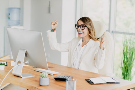 Young businesswoman celebrating success in modern office environment wearing elegant attireの写真素材