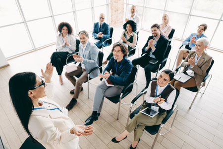 Businesswoman addressing team during a corporate seminar emphasizing teamwork and collaboration in a modern office settingの写真素材