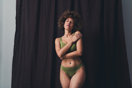 Photo of lovely young lady enjoy hug self dressed khaki lingerie studio background no filter self acceptance all body perfectの写真素材