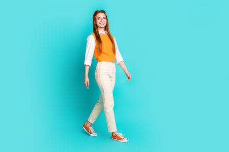 Full length photo of adorable lovely girl wear stylish outfit going empty space isolated on aquamarine color backgroundの写真素材