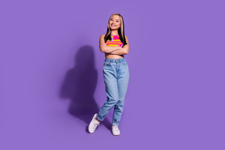 Photo of lovely cute smiling girl wear stylish clothes standing with folded arms isolated on purple color backgroundの写真素材
