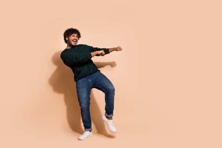 Full size photo of nice young man dance empty space wear sweater isolated on beige color backgroundの写真素材