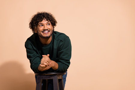 Photo of handsome guy wear sweatshirt smiling looking empty space isolated beige color backgroundの写真素材
