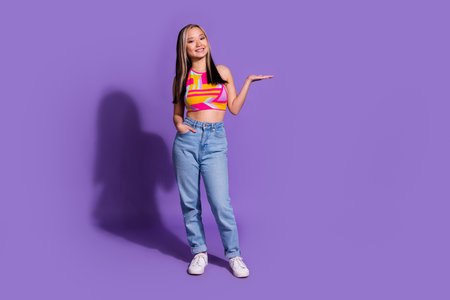 Photo of cheerful lovely cute girl wear stylish clothes arms hold empty space isolated on purple color backgroundの写真素材