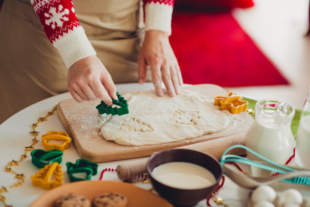 Funny cozy holiday baking moment with dough rolling and festive cutters in a warm indoor scene under Christmas lightsの写真素材