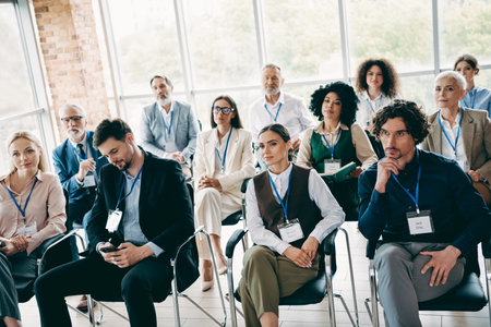 Professionals attentively interacting during a corporate conference in a modern office space highlighting teamwork and discussionsの写真素材