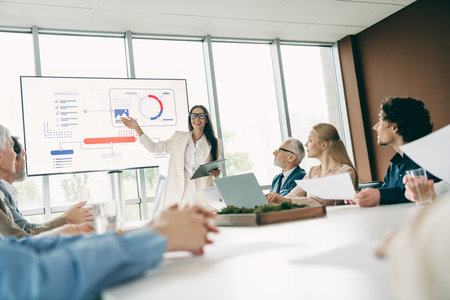 Professional business team discussing strategies during a corporate presentation in a modern office workspaceの写真素材